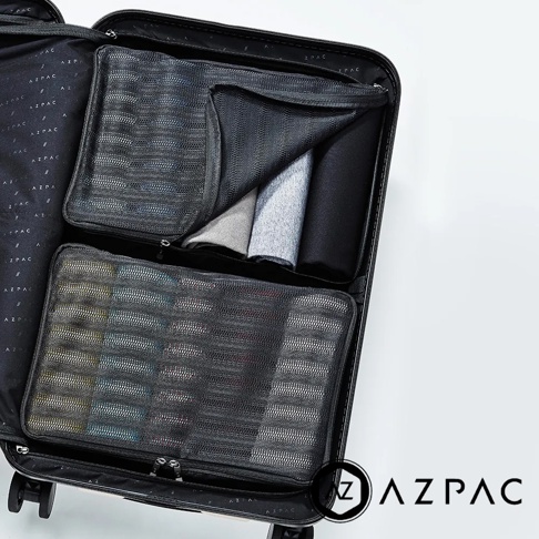 AZPAC 品牌 logo 出現在黑色行李箱中，箱內有兩個網狀收納袋，上方收納袋內有摺疊的灰色與黑色衣物，下方收納袋內裝有整齊排列的物品。