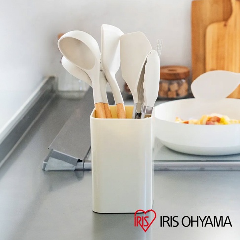 米白色收納架裝有廚房用具，包括湯勺、鍋鏟、夾子等，多數為米白色矽膠材質，手柄帶有木紋。