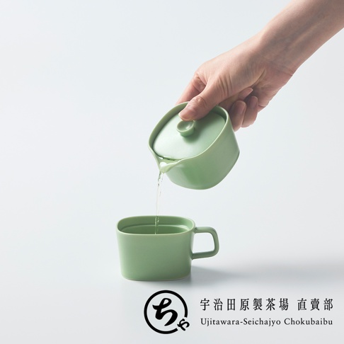 一隻手正握著宇治田原製茶場的淺綠色美濃燒一人用茶壺，將茶水注入下方配套的茶杯中，簡約的設計與素雅的色調呈現出寧靜的品茶氛圍，右下方標註有宇治田原製茶場直賣部的商標文字。