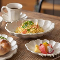 六魯粉引花型橢圓料理盤，以白色陶瓷製成，盤緣呈現花瓣狀，盤中盛有義大利麵，旁邊擺放著咖啡杯、麵包和水果盤。