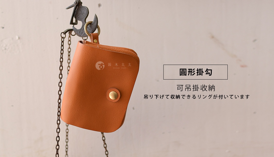 棕褐色皮革雙層旅行錢包，附有金屬按扣及掛繩，懸掛於復古掛鉤上。