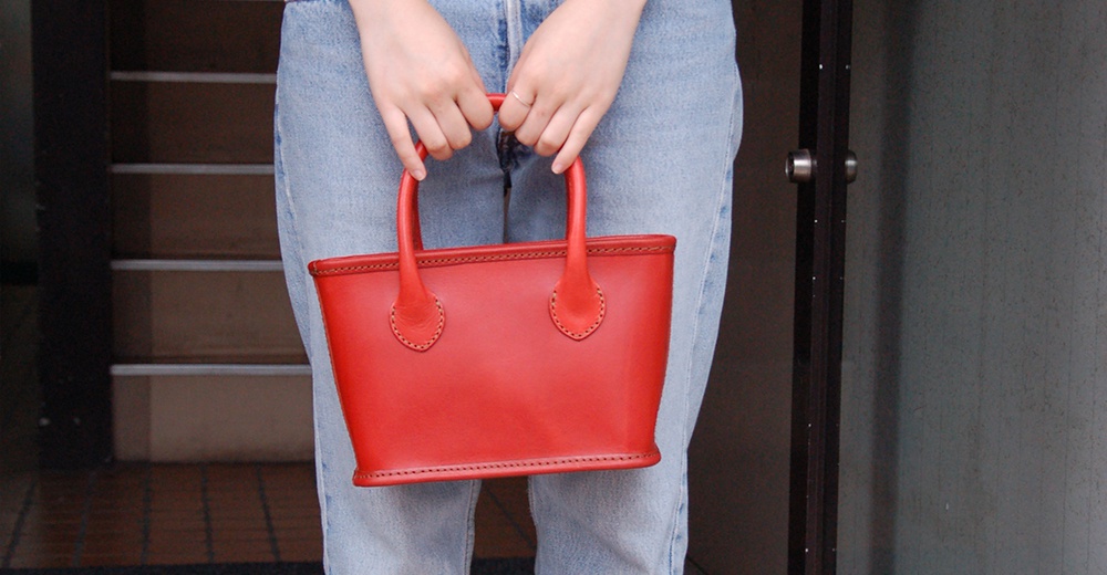 紅色皮革輕巧散步手提包，款式簡約，配有兩條提把，適合日常攜帶。