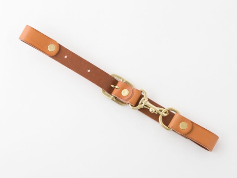 職人手作皮革背包用胸前扣帶，寬2.4cm，採用棕色皮革製作，配有黃銅色金屬扣件、旋轉鉤和D型環，用於固定和調整。