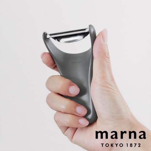 marna 品牌的多功能削皮器，由手部握持，特寫鏡頭。