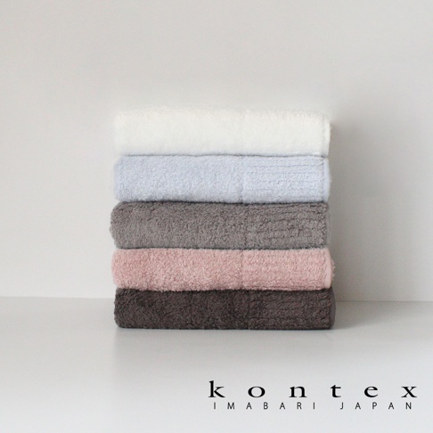 堆疊的五條今治毛巾，顏色從上到下分別為白色、淺藍色、灰色、粉紅色和深棕色，毛巾質地蓬鬆柔軟。