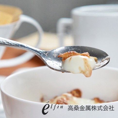 日製不鏽鋼湯匙，表面有錘目紋，盛著白色甜點與焦糖醬。