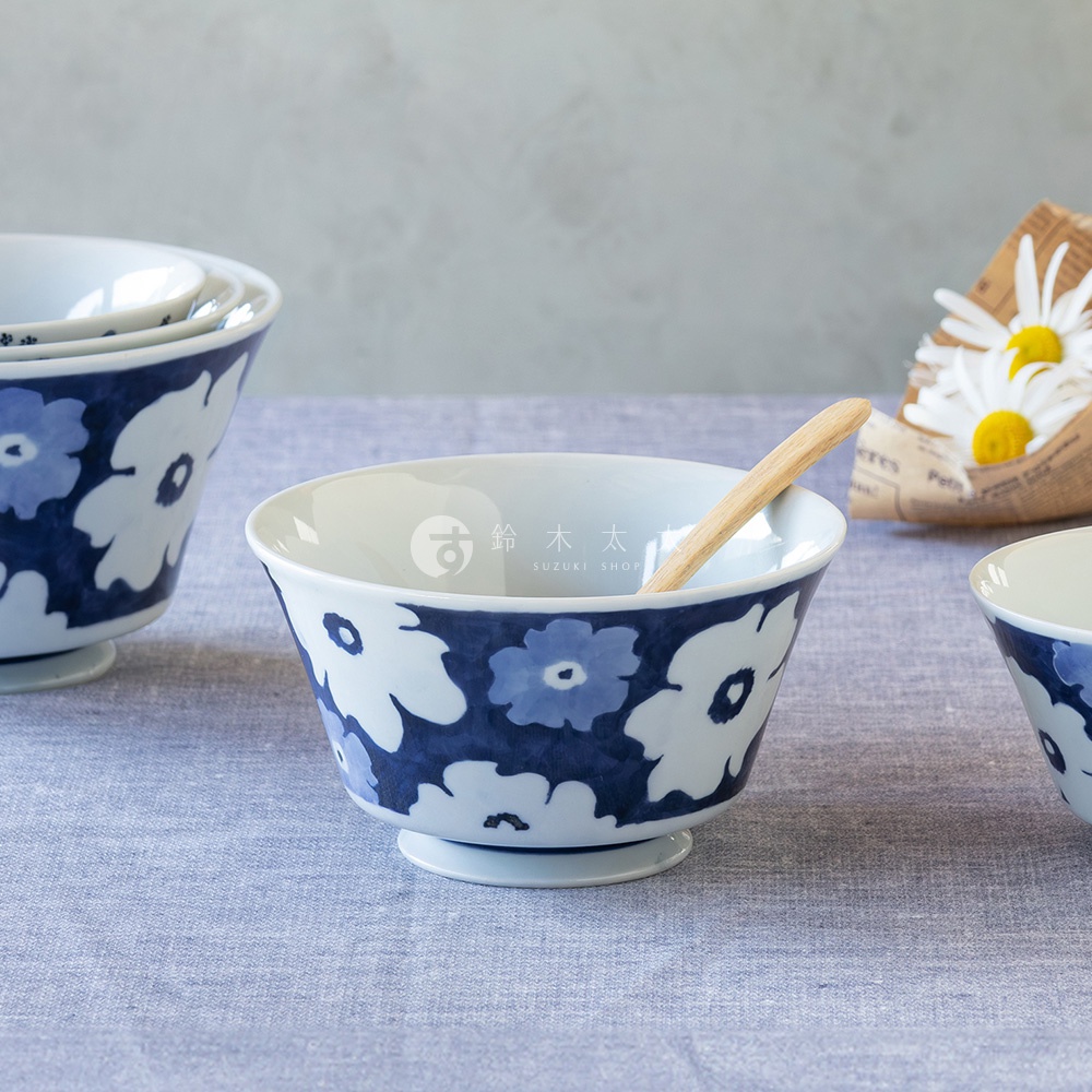 白底藍色花紋的陶瓷丼飯碗，碗身繪有大小不一的藍色花朵圖案，碗底有穩固的圓形座。