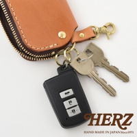 職人手作皮革鑰匙包，淺棕色皮革，附有黃銅色拉鍊、兩個鑰匙圈、一個汽車遙控器和兩把銀色鑰匙。