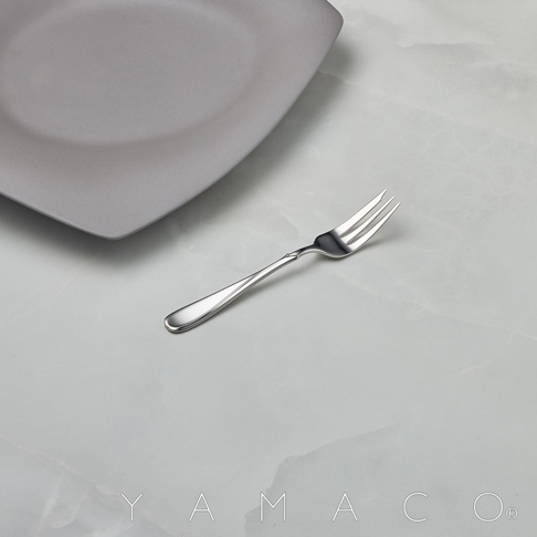 Flora系列不鏽鋼點心叉，呈現優雅的扭紋設計，搭配灰色方形盤，置於大理石紋桌面，視覺簡潔精緻。