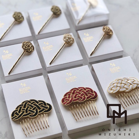 和風水引花結金絲髮叉，包含金、米白、紅、黑四色。髮叉頂端為精緻的水引花結，搭配金色金屬髮簪或梳齒。產品以白色卡紙包裝，部分髮叉以透明盒包裝。