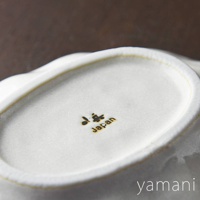 白色陶瓷橢圓料理盤，邊緣帶有細緻的黃色線條，盤底印有金色「小兵」字樣及「Japan」字樣。