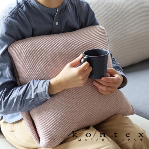 粉色羅紋針織彈性枕套，質地柔軟，觸感舒適。一人抱著枕頭，手持黑色馬克杯，坐在沙發上。