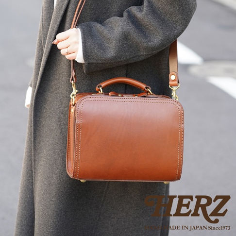 職人手作皮革兩用方形單肩包，展示為經典棕色，採用光滑皮革材質，搭配頂部提把及可拆卸肩帶，金屬扣件增添質感。