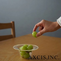 一個透明玻璃製成的深型點心碗，碗中盛有幾串綠色葡萄，一隻手正從碗中拿起一顆葡萄。