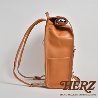 棕色皮革後背包，側邊視角，皮革材質，配有可調整的肩帶和金屬扣環，包身有外層口袋，頂部採捲口設計。