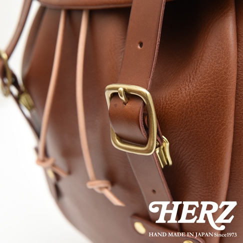 職人手作皮革經典雙扣後背包 R-152，採用棕色皮革，配有黃銅色金屬扣環和束繩設計。