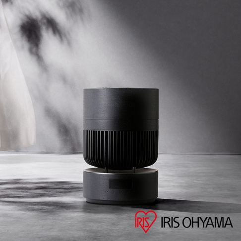 IRIS OHYAMA 360度美型空氣循環扇 PCF-CDP18TEC，黑色圓柱狀機身設計，上方為格柵狀送風結構，下方底座設有顯示面板與觸控按鍵，整體外觀簡約現代，放置於水泥質感地面上。