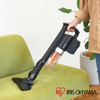 黑色氣旋式超輕量無線手持吸塵器，配有透明集塵筒和橘色濾網，正被手持清潔綠色布藝沙發。