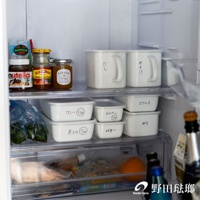 冰箱內層架上擺放著幾個白色方型密封蓋琺瑯保存容器，其中兩個較大的容器帶有把手，上面分別寫有日文「だし」和「みそ汁」。下方還有較小的白色保存容器，標示著「カレー」、「おひたし」、「煮もの」、「バター」和「ピクルス」等字樣。