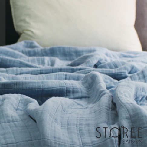 淺藍色九層紗單人毯，質地輕柔，帶有紋理，鋪在床上，背景為白色枕頭。