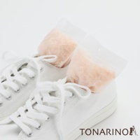 一雙白色帆布鞋，鞋內各放入一個透明小包裝的檜木屑除濕消臭包，包內為淺橘色顆粒狀材質。