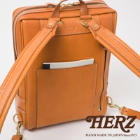 職人手作皮革軟皮商務後背包，採用溫暖的棕褐色皮革，縫線清晰，設有外插袋可放置筆記本，搭配品牌標誌，展現精緻工藝。