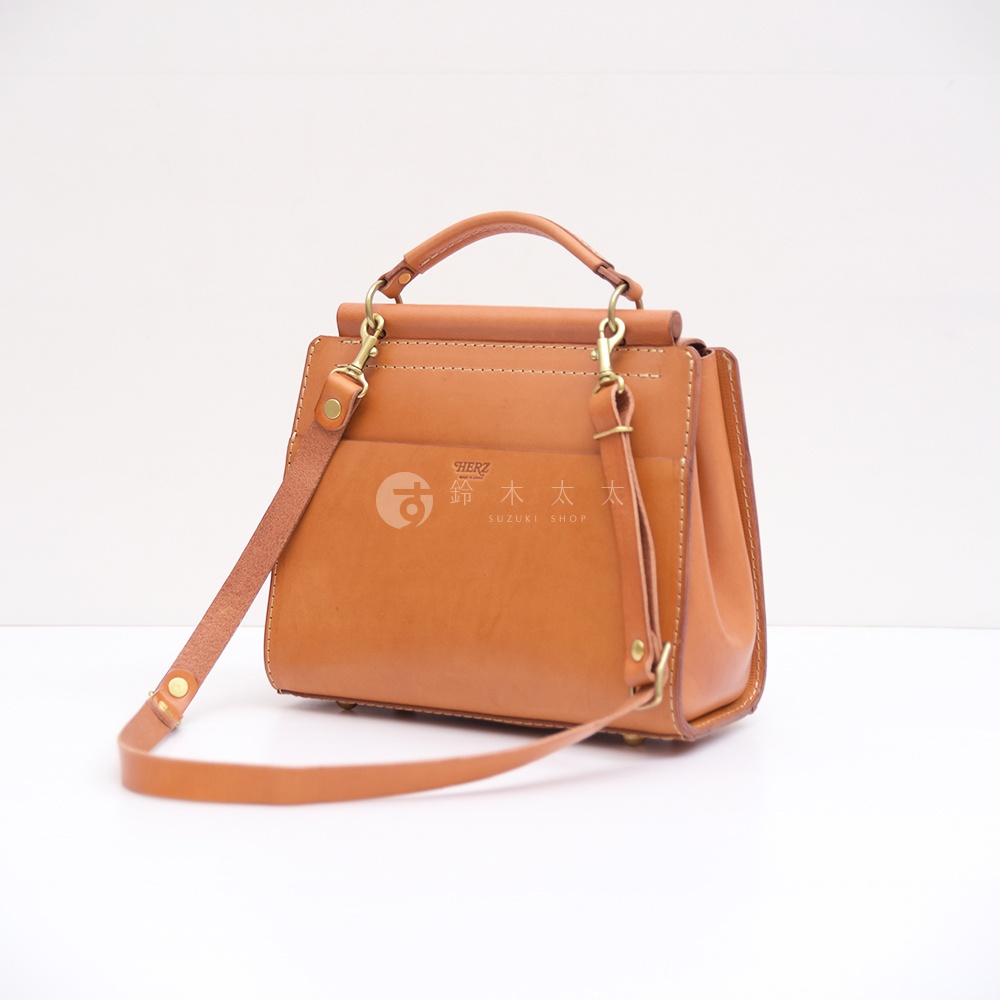 日本HERZ職人手作淺棕色皮革屋瓦風兩用單肩包，可手提、肩背或斜背，設有品牌標誌。