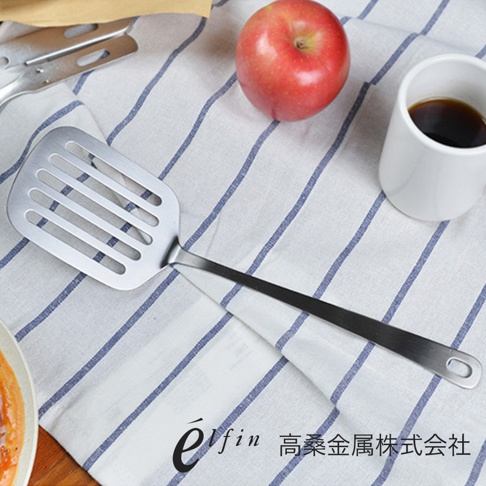 日製不鏽鋼輕薄煎匙，銀色，帶有長條狀的鏤空孔洞，適合煎魚或翻炒食物。