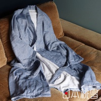 藍色異素材紗質浴袍，領口、袖口和腰帶為白色內裡，搭配咖啡色燈芯絨沙發。