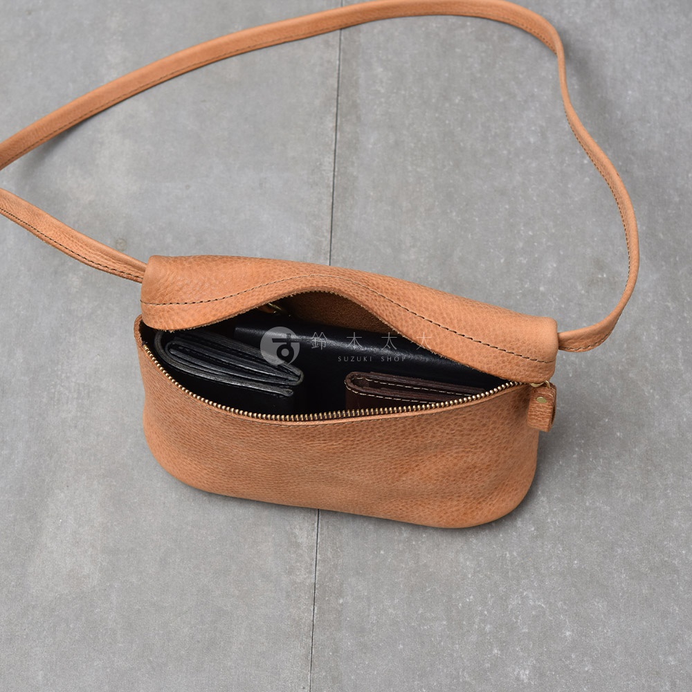 一個棕褐色皮革斜背包，敞開的拉鍊處可見黑色錢包和一個深棕色錢包。