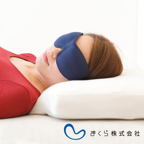 一位女子戴著深藍色零壓感舒眠眼罩，側臥在白色網狀織物枕頭上，身穿紅色上衣。