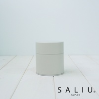 簡約的淺灰色圓柱形錫製茶葉罐，帶有蓋子，底部和蓋子邊緣有細微的銀色線條裝飾，放置於白色木紋背景上。