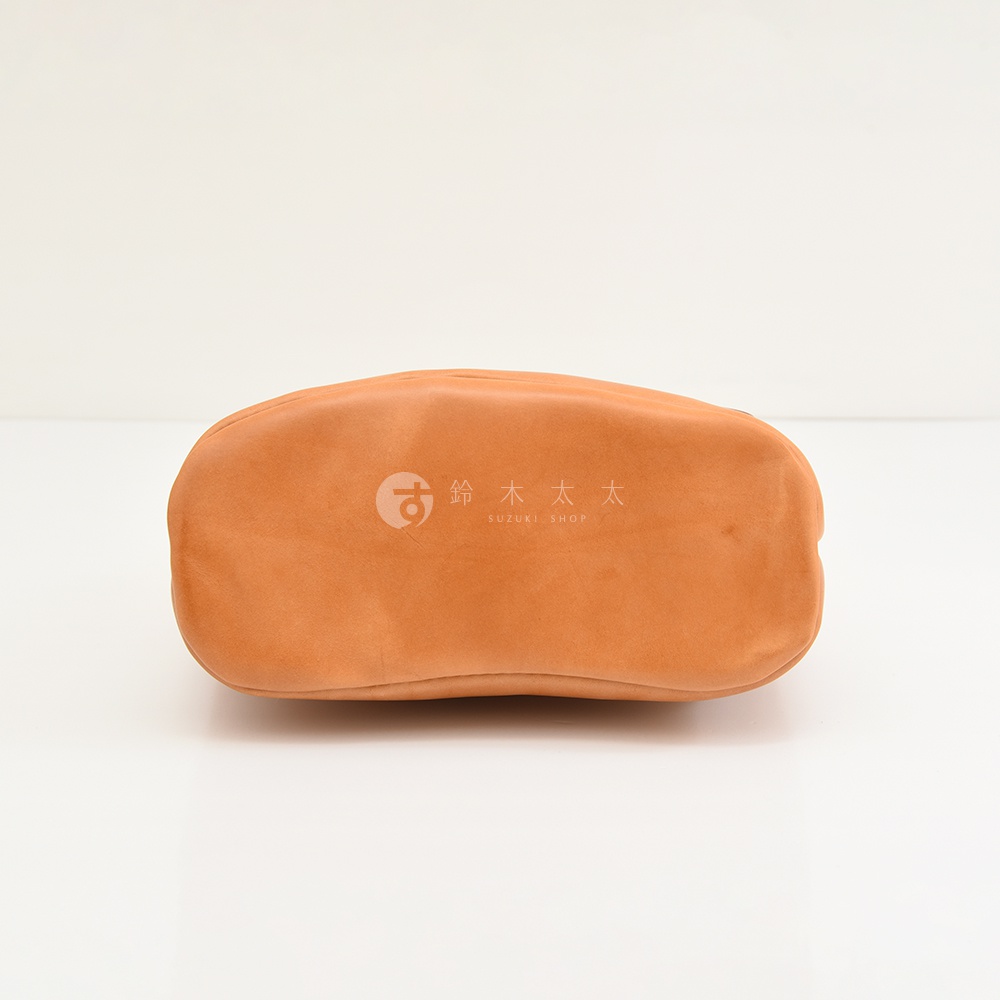 可見皮革包底部，上面壓印有「SUZUKI SHOP」和日文文字。