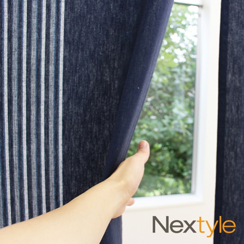 深藍色純棉門簾，帶有白色及淺藍色細條紋，一隻手正輕輕拉開門簾，露出窗外的綠色樹葉。