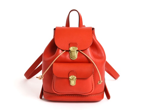 亮橙色皮革迷你後背包，帶有頂部提把、可調節肩帶、正面翻蓋設計、雙扣環閉合，以及一個帶有鈕扣的小前袋。