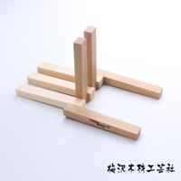 淺色木製翻轉隔熱墊，由多塊方形木條組成，部分木條帶有刻字。