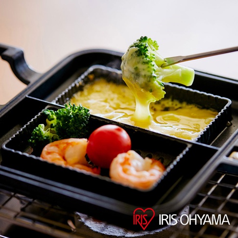 黑色直火專用熱壓三明治夾烤盤，內有兩個獨立烤槽，烤槽內裝有融化的起司、青花菜、小番茄和蝦子。