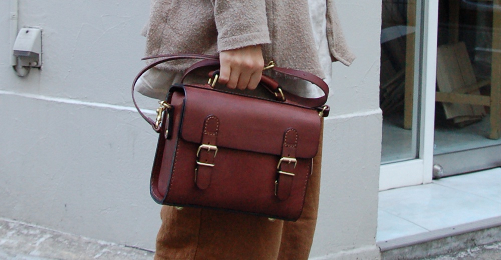 深紅色皮革迷你兩用包，配有金屬扣環和可拆卸肩帶，由人手製作。