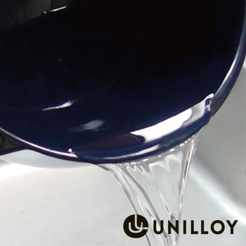 深藍色琺瑯鑄鐵鍋傾斜，鍋內的水流出，鍋邊緣有反光。