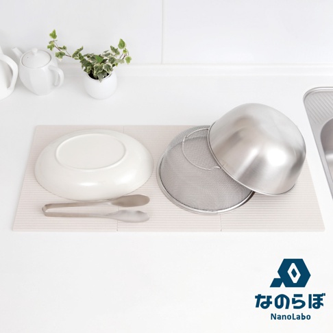 NANOLABO 組合包含 UB 米之守護神防潮塊和 UB 瞬間吸水置物墊，白色餐具和濾網放置在淺色條紋墊上，旁邊還有一個白色茶壺和植物。