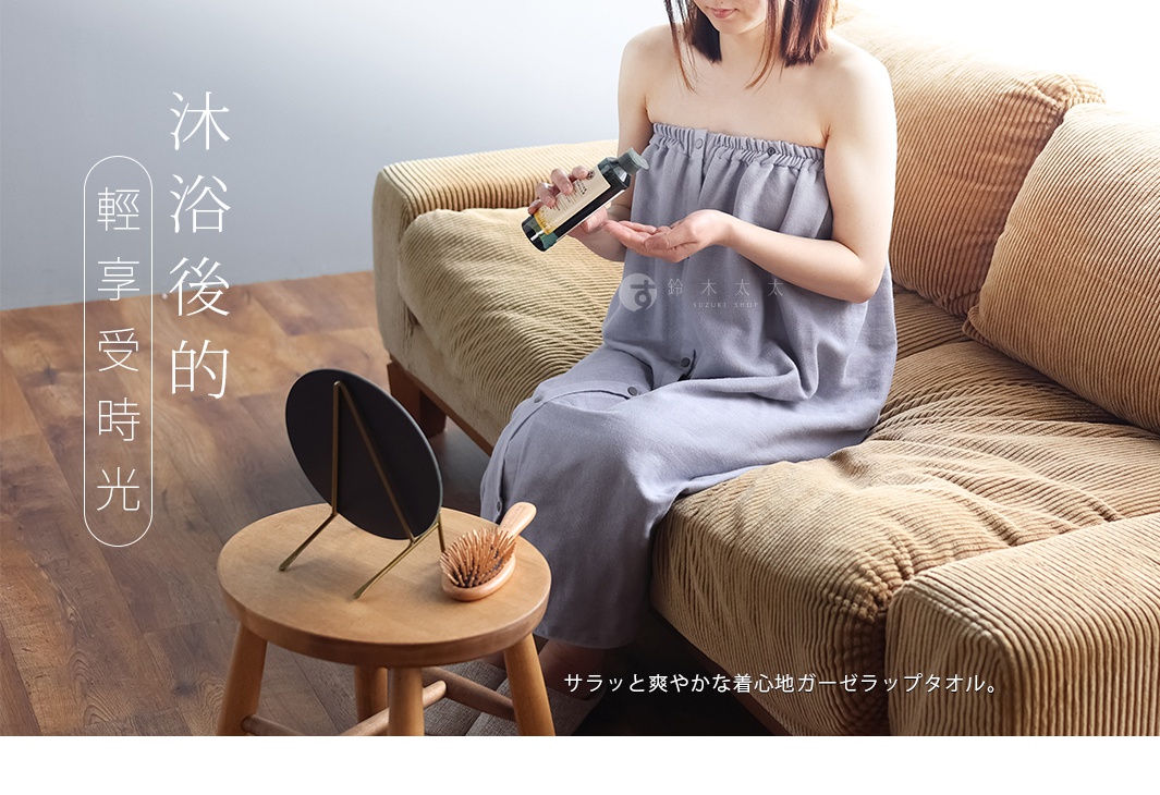 一位女性身著淺藍色棉紗混紡平口鬆緊浴裙，坐在棕色燈芯絨沙發上，手持一瓶化妝品。