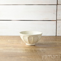 米白色的陶瓷丼碗，碗身有六道凹槽紋路，底部有圓形底座，碗緣略向外翻，置於木紋桌面上。