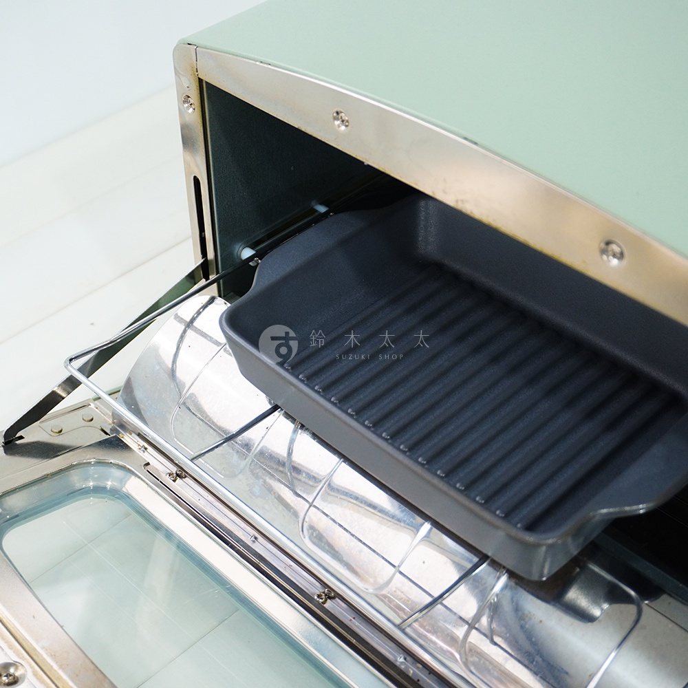 淺綠色烤箱內，擺放著一個黑色、帶有波浪紋的長方形烤盤。