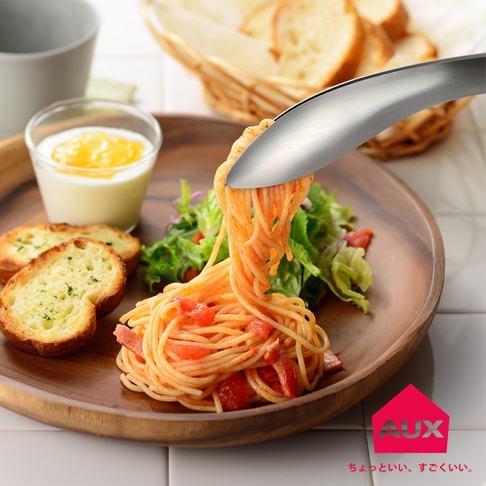 leye 不沾桌曲型分菜夾，銀色不鏽鋼材質，設計成彎曲造型，正夾著一盤番茄義大利麵，旁邊擺有蒜味麵包、沙拉和一杯優格。