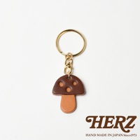 皮革香菇造型鑰匙圈，傘蓋為深棕色皮革，點綴三個淺棕色圓點，傘柄為淺棕色皮革。配有金色鑰匙圈與鉤環。