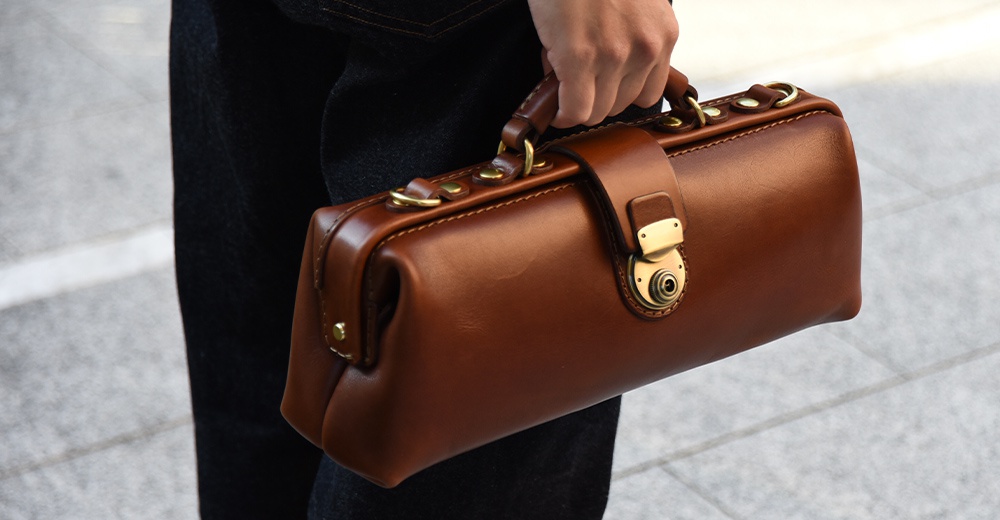 日本HERZ職人手作皮革橫長形杜勒斯單肩包 CW-4，由Latigo軟皮革製成，配有金色鎖扣，由手持。