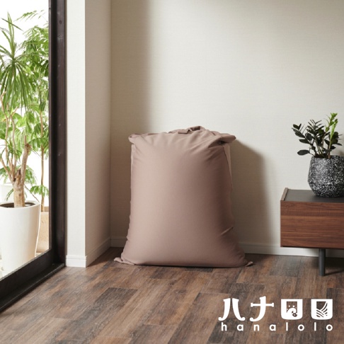 一組大型的懶骨頭沙發，採用柔軟的針織布料製成，呈現柔和的淺棕色。沙發放置在木紋地板上，一旁有綠色植物點綴。