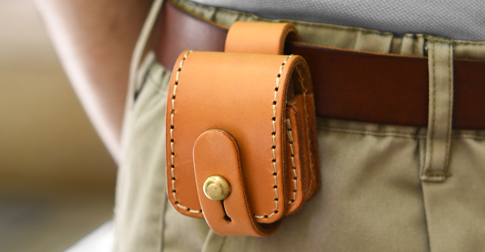 淺棕色植鞣皮革製成、附有原子釦的腰間小物收納包，側邊及邊緣有縫線裝飾，可掛於皮帶上。