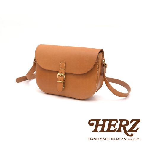 職人手作皮革經典馬鞍包，採用天然棕色皮革製成，配有黃銅色皮帶扣和可調節肩帶，風格簡約。