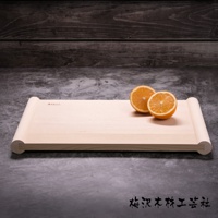 淺色木質砧板，有捲軸狀的邊緣，上面放著兩半切開的橘子。